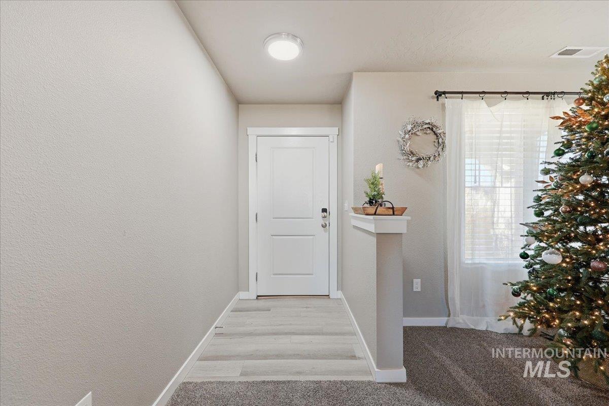 Doorway to outside featuring a textured wall and carpet