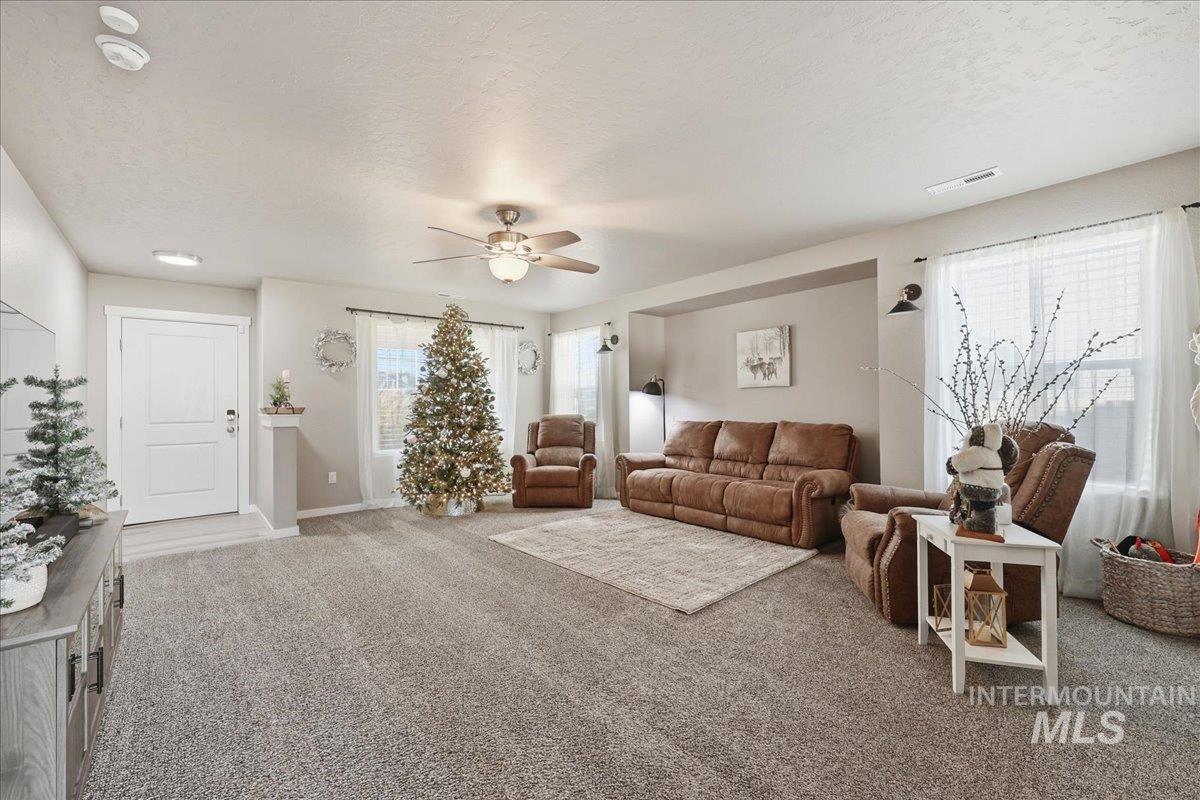 Living area featuring a textured ceiling, carpet, and ceiling fan