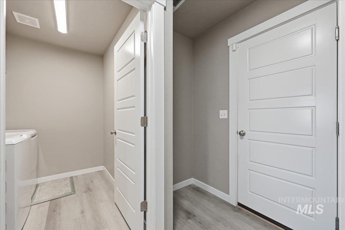 Laundry room with light wood-type flooring and washing machine and dryer