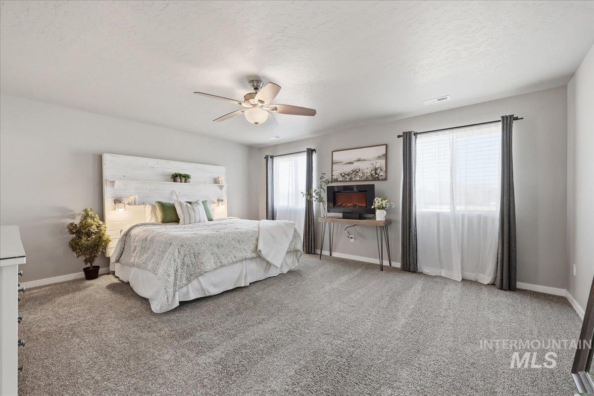 Bedroom with light colored carpet, a textured ceiling, and a ceiling fan