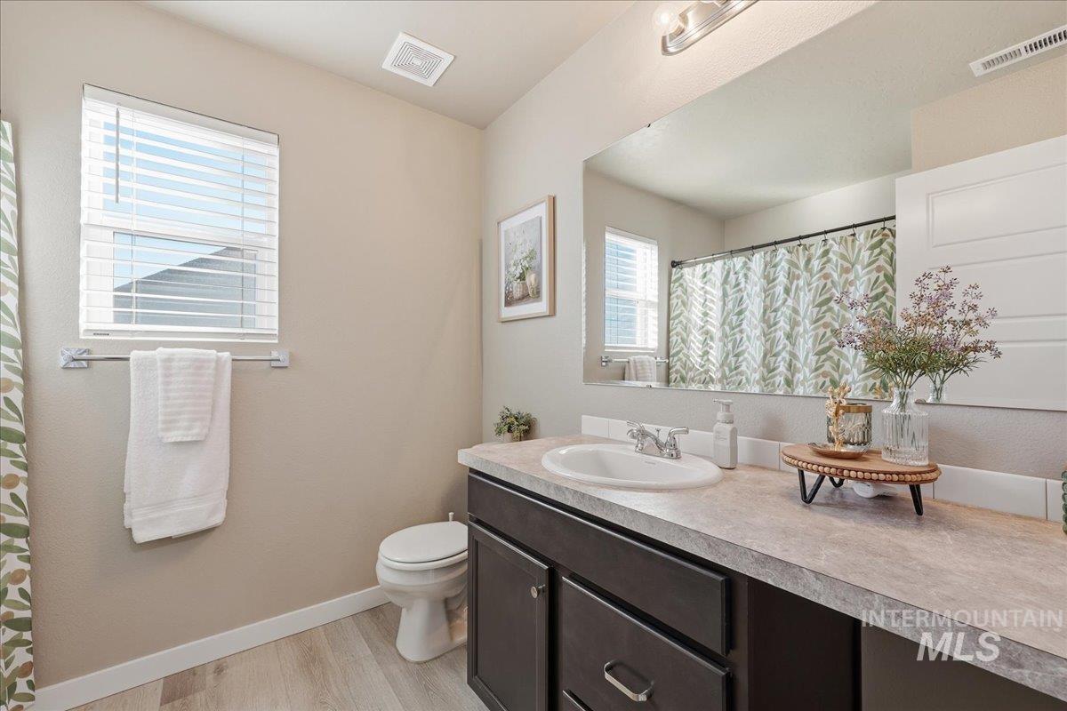 Full bath with a shower with shower curtain, vanity, and light wood-style floors
