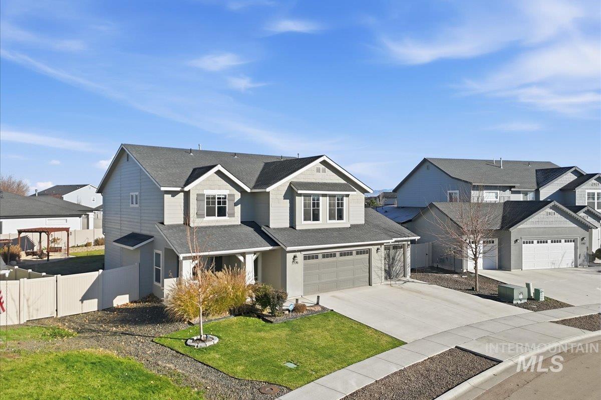 Traditional-style house featuring a residential view, concrete driveway, an attached garage, and roof with shingles