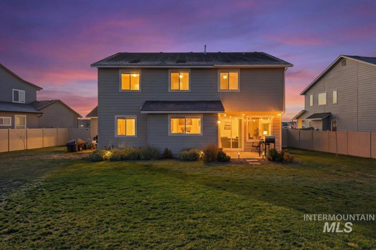 Back of house at dusk featuring a fenced backyard and a patio area
