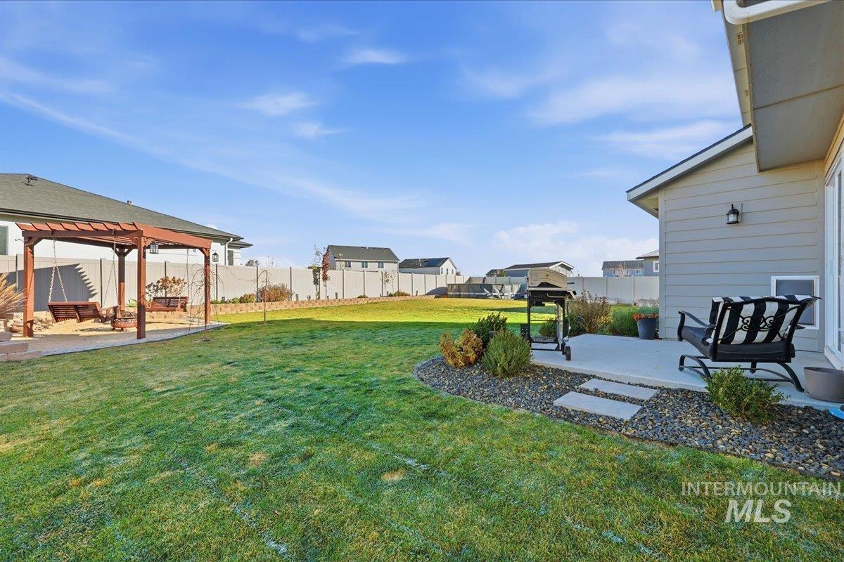 Fenced backyard with a patio, a residential view, and a pergola