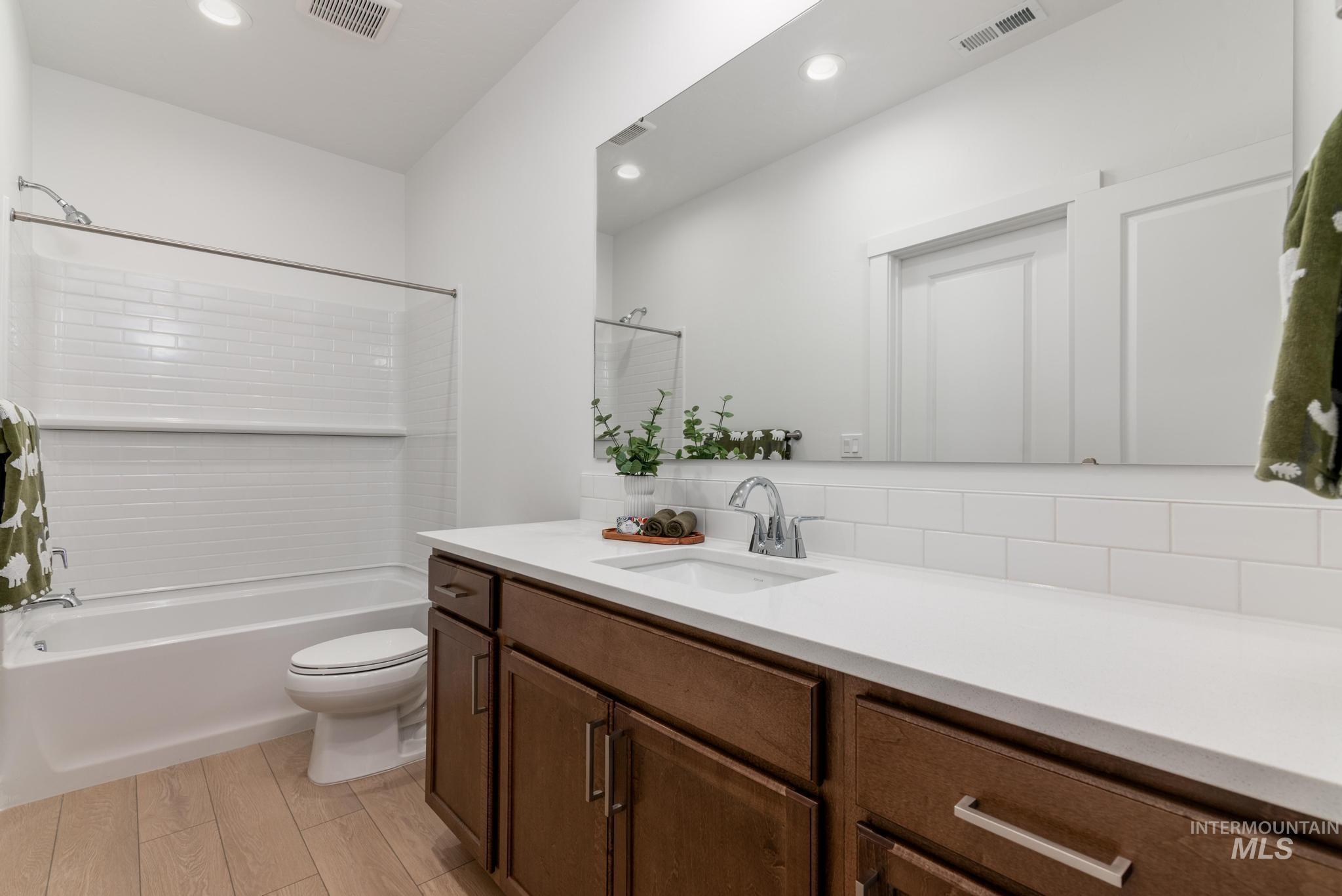 Bathroom with vanity, bathing tub / shower combination, light wood-style flooring, recessed lighting, and tasteful backsplash
