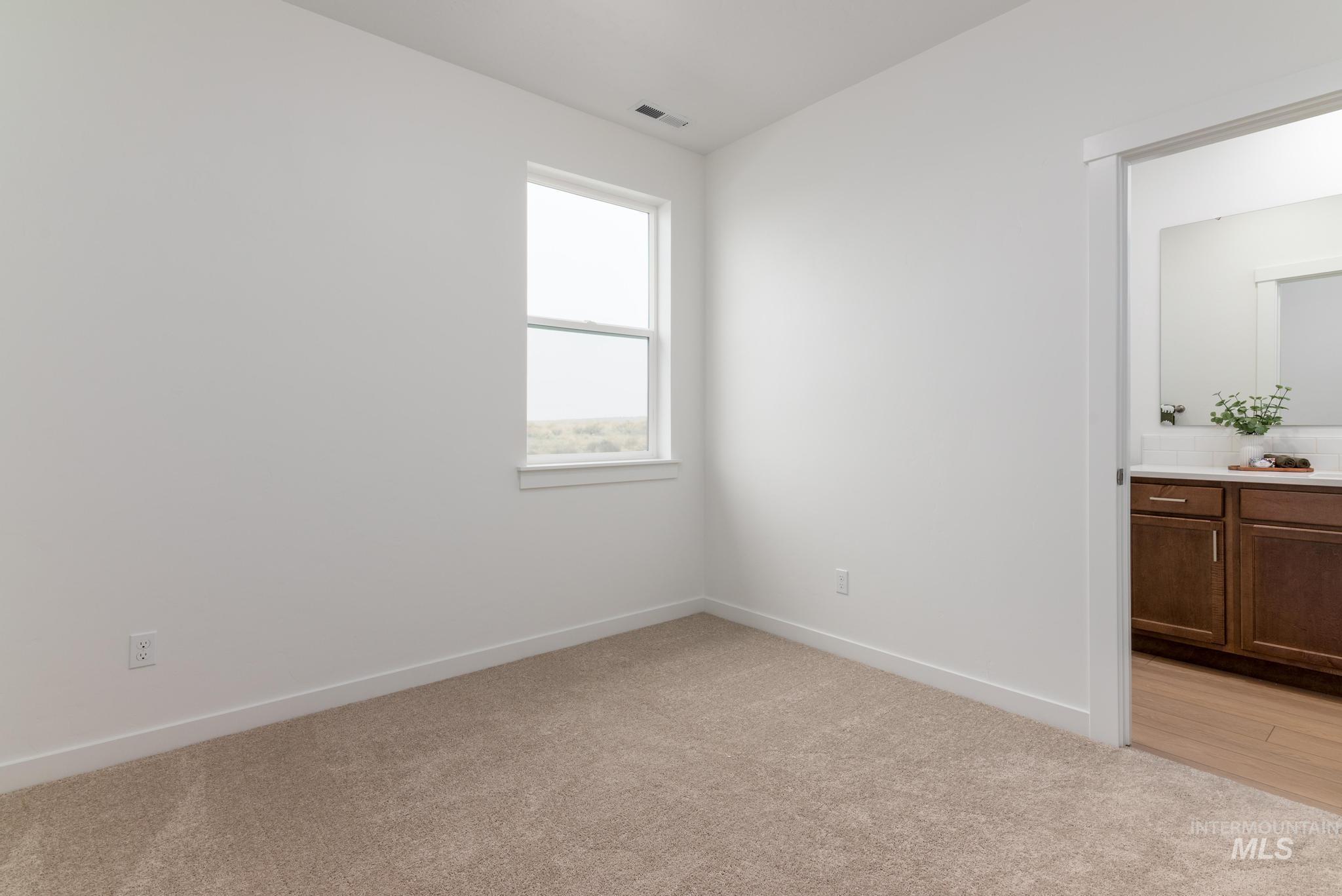 Unfurnished bedroom featuring light colored carpet and ensuite bathroom