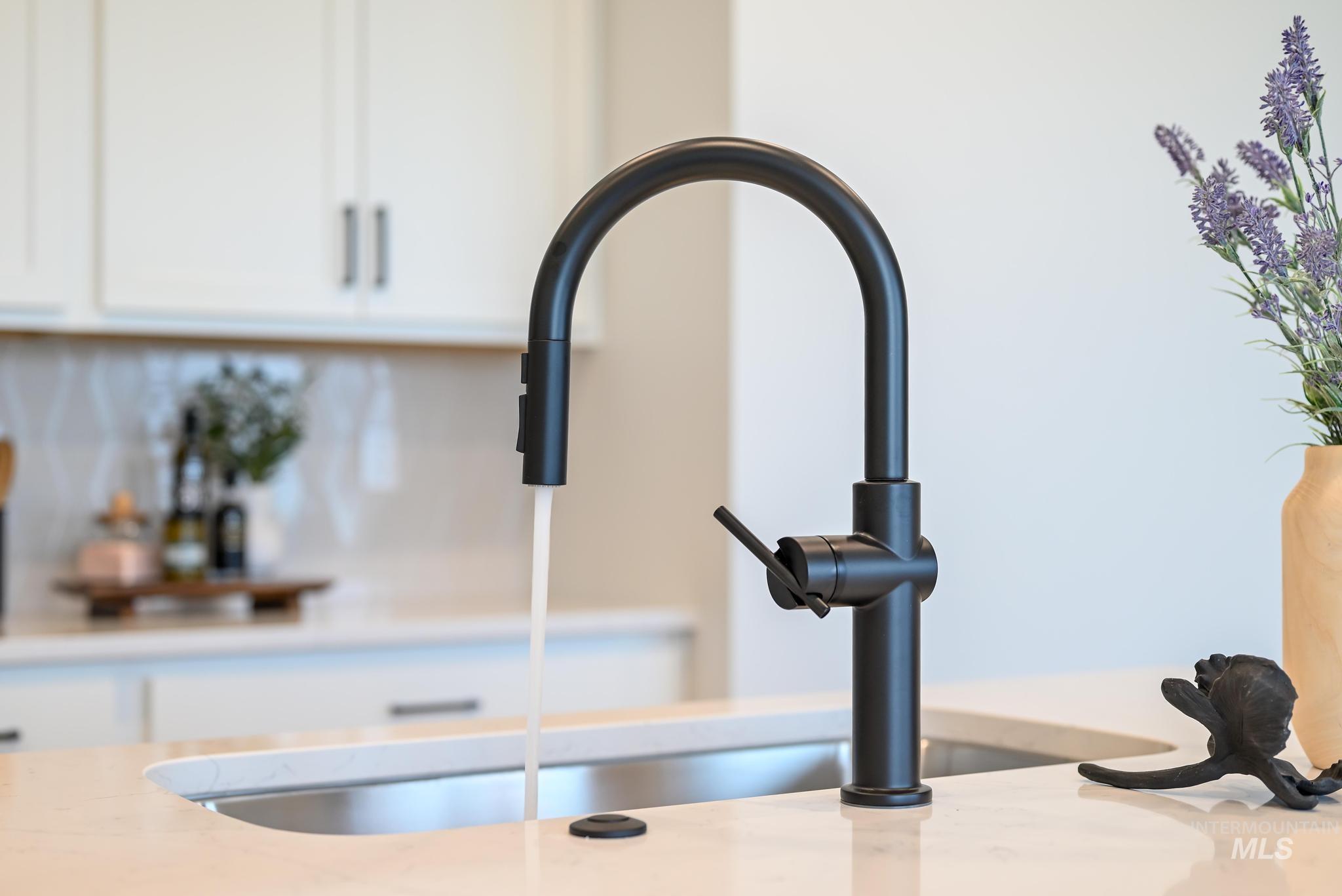 Kitchen view of white cabinetry, backsplash, and light stone countertops