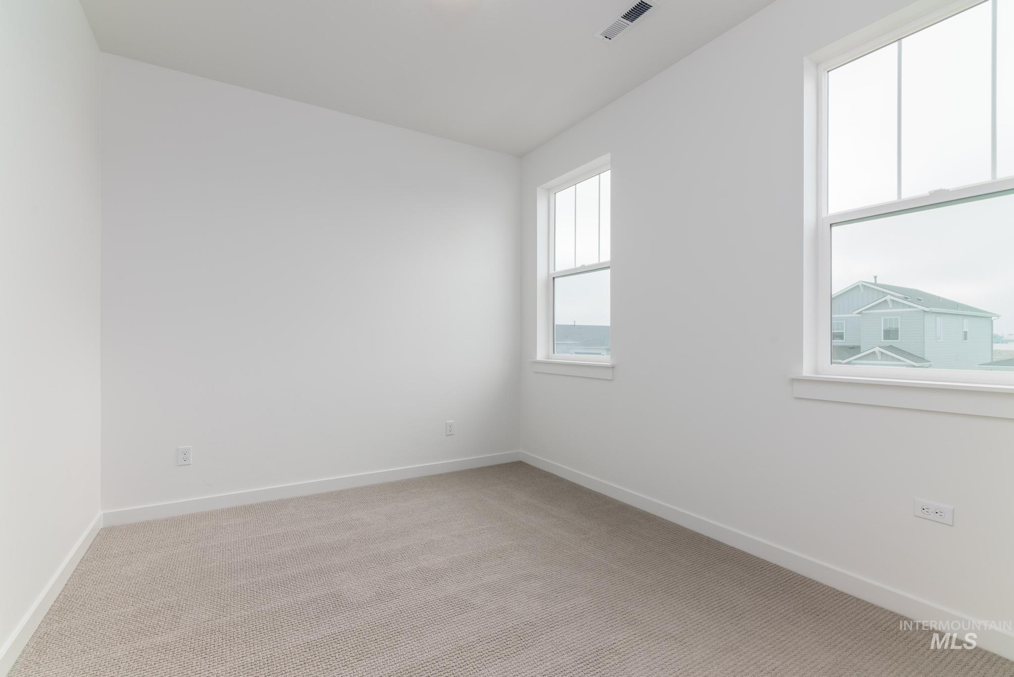 Spare room featuring light carpet and baseboards