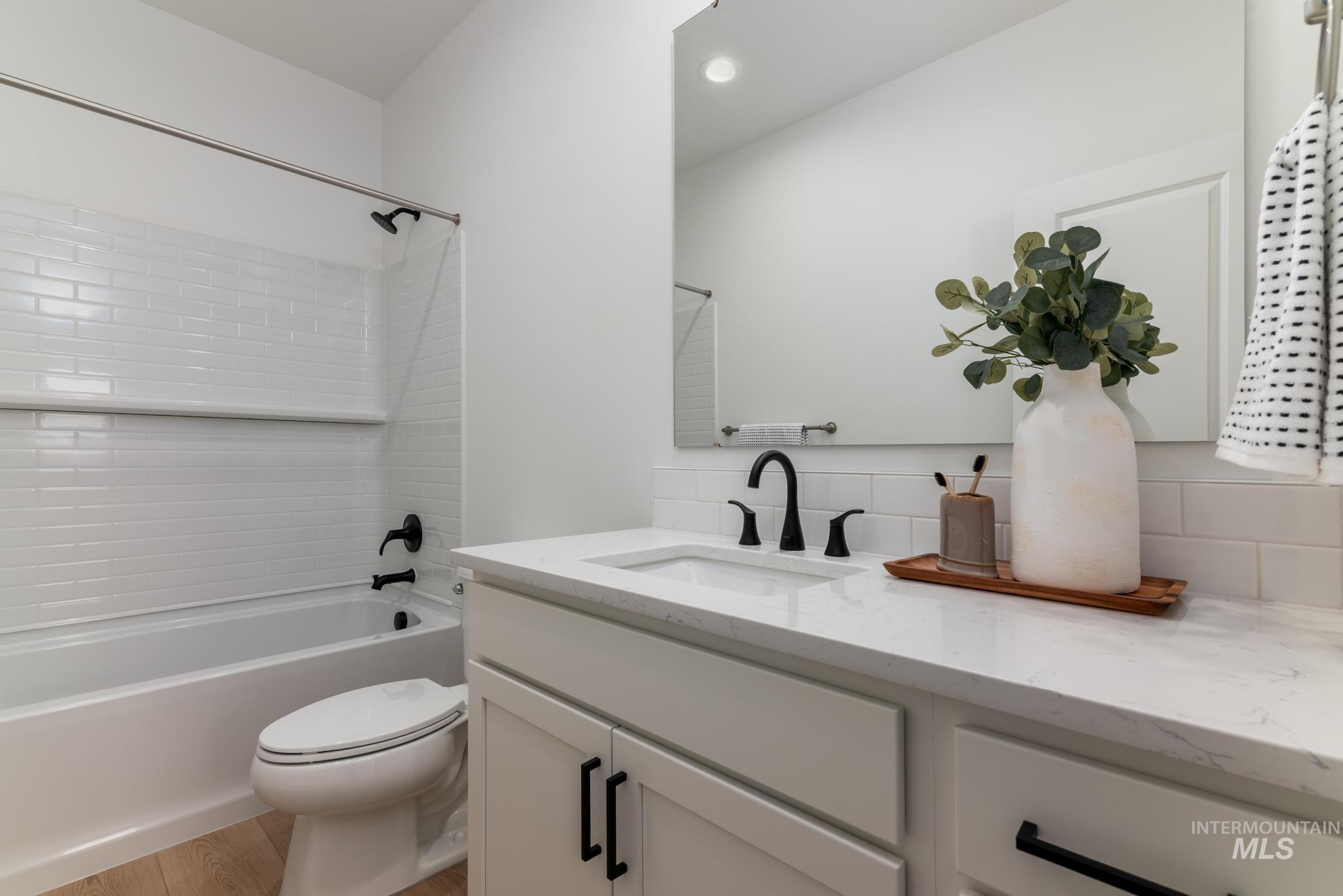 Full bathroom with vanity, shower / bath combination, decorative backsplash, and light wood-type flooring