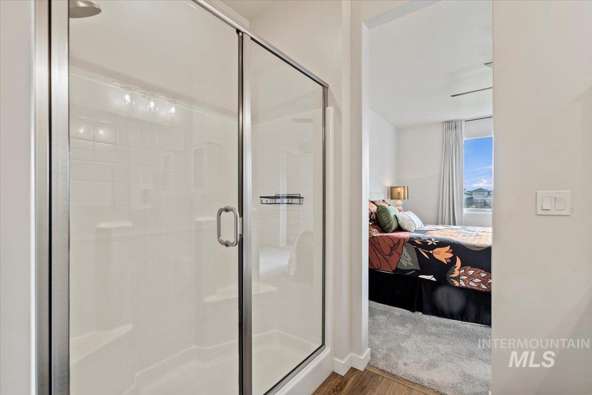 Ensuite bathroom with a stall shower and wood finished floors