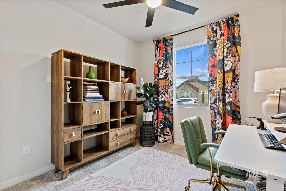 Carpeted home office featuring baseboards and a ceiling fan