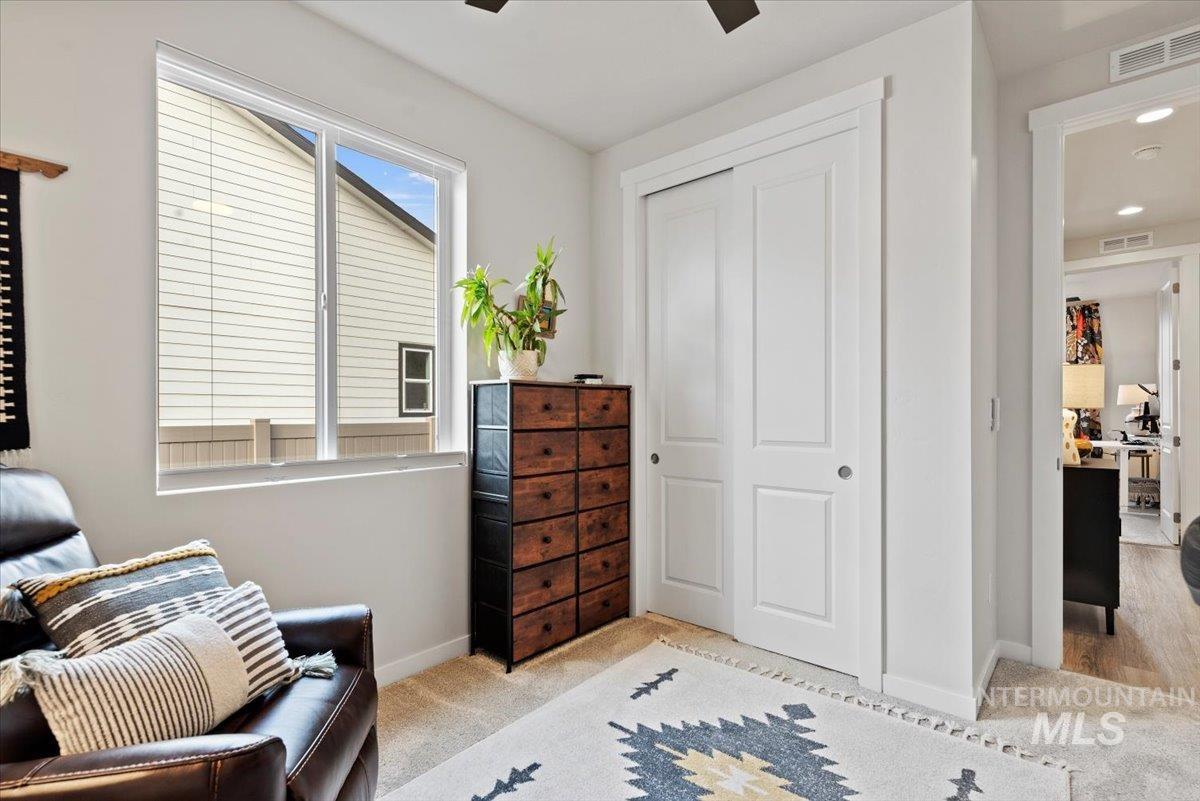 Sitting room featuring light colored carpet and a ceiling fan