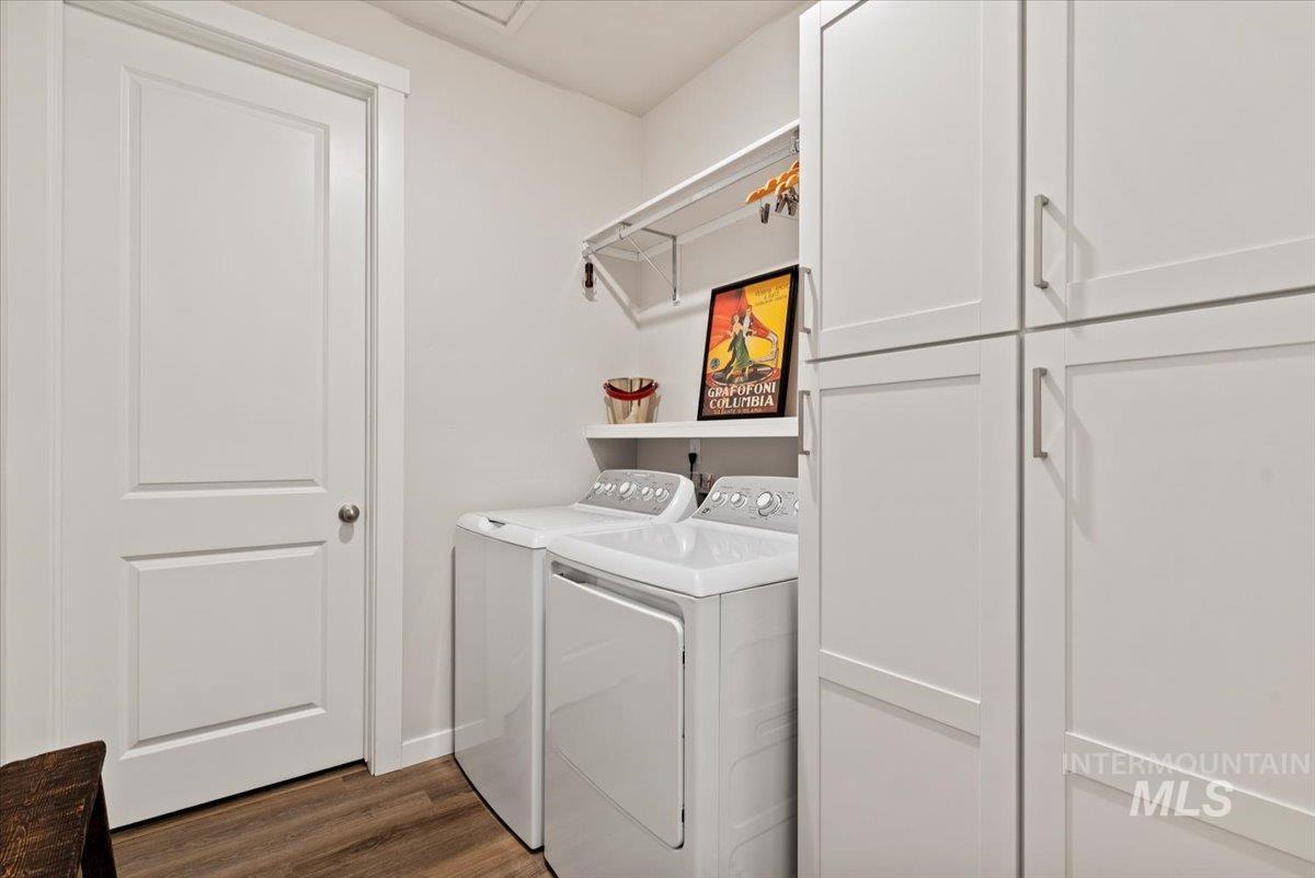 Laundry room with cabinet space, dark wood-style floors, and washer and clothes dryer