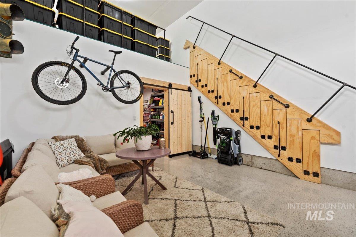 Living room featuring a barn door, a towering ceiling, finished concrete floors, and stairs