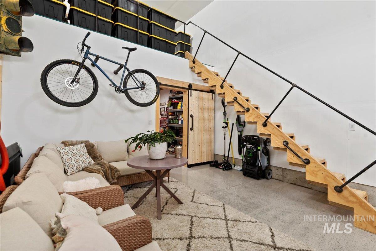 Living room with a barn door, stairs, and finished concrete flooring