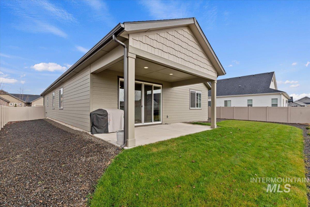 Back of house with a fenced backyard and a patio