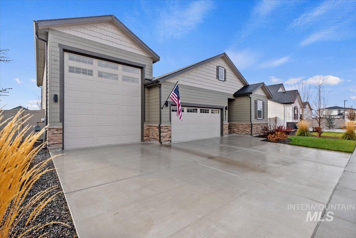 View of front of home with stone siding, an attached garage, and concrete driveway