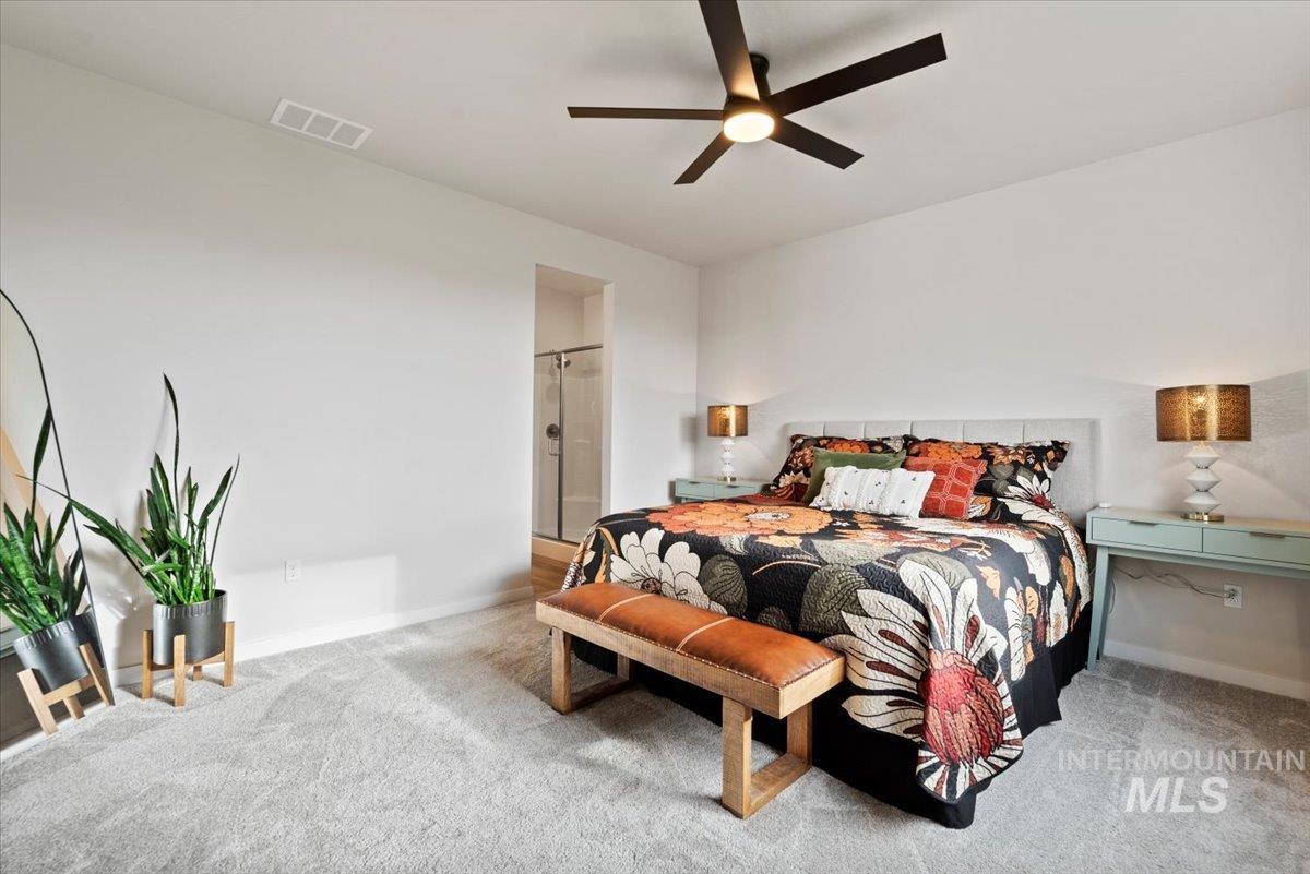 Carpeted bedroom featuring ceiling fan and ensuite bath