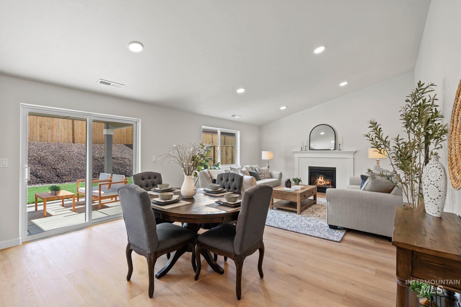 Dining room featuring a glass covered fireplace, plenty of natural light, light wood-style floors, recessed lighting, and vaulted ceiling