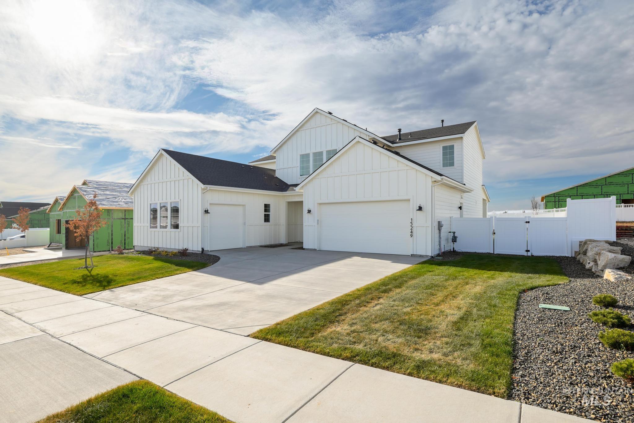 View of front of property with a gate, board and batten siding, driveway, and an attached garage
