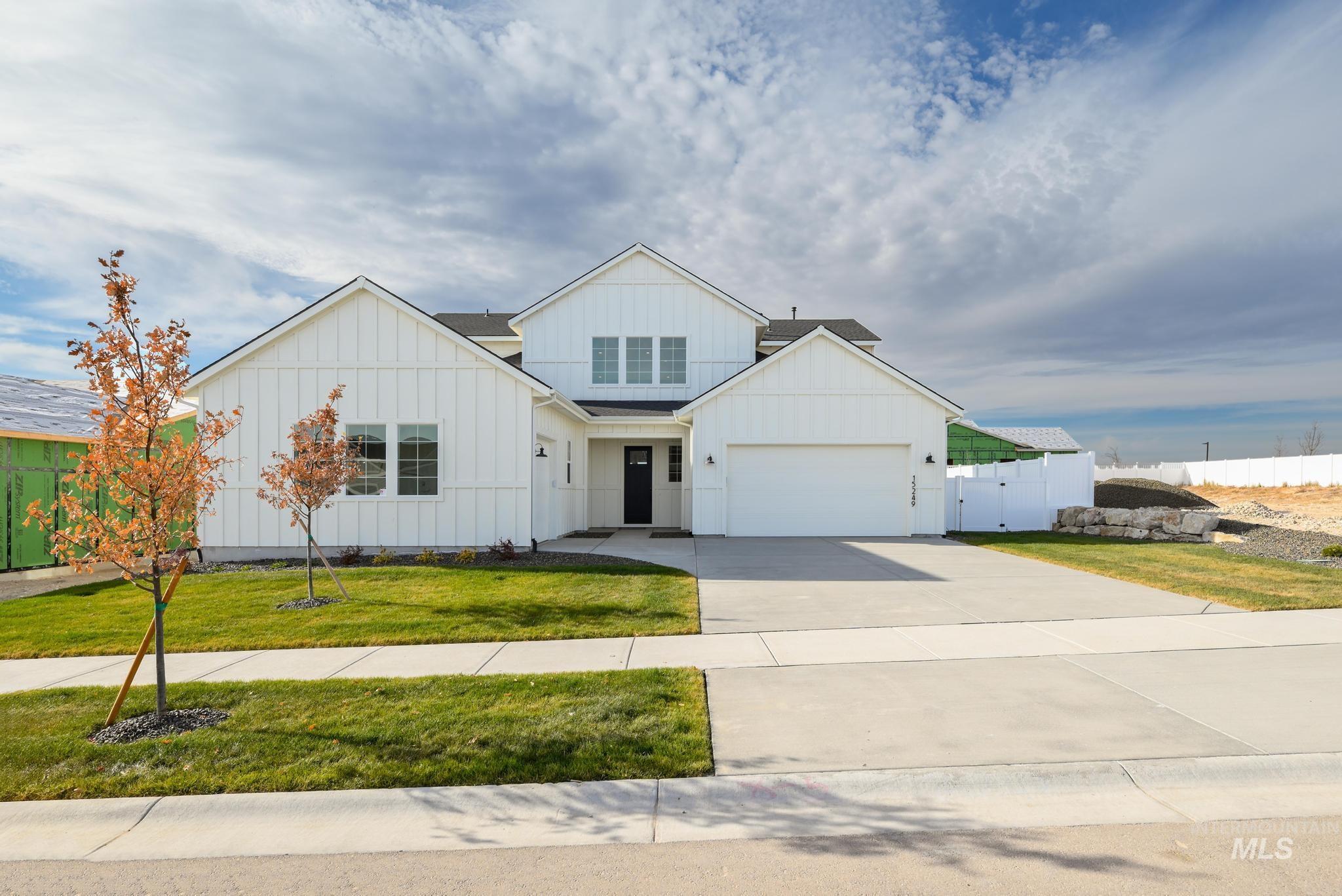 Modern farmhouse style home featuring board and batten siding, driveway, and a gate