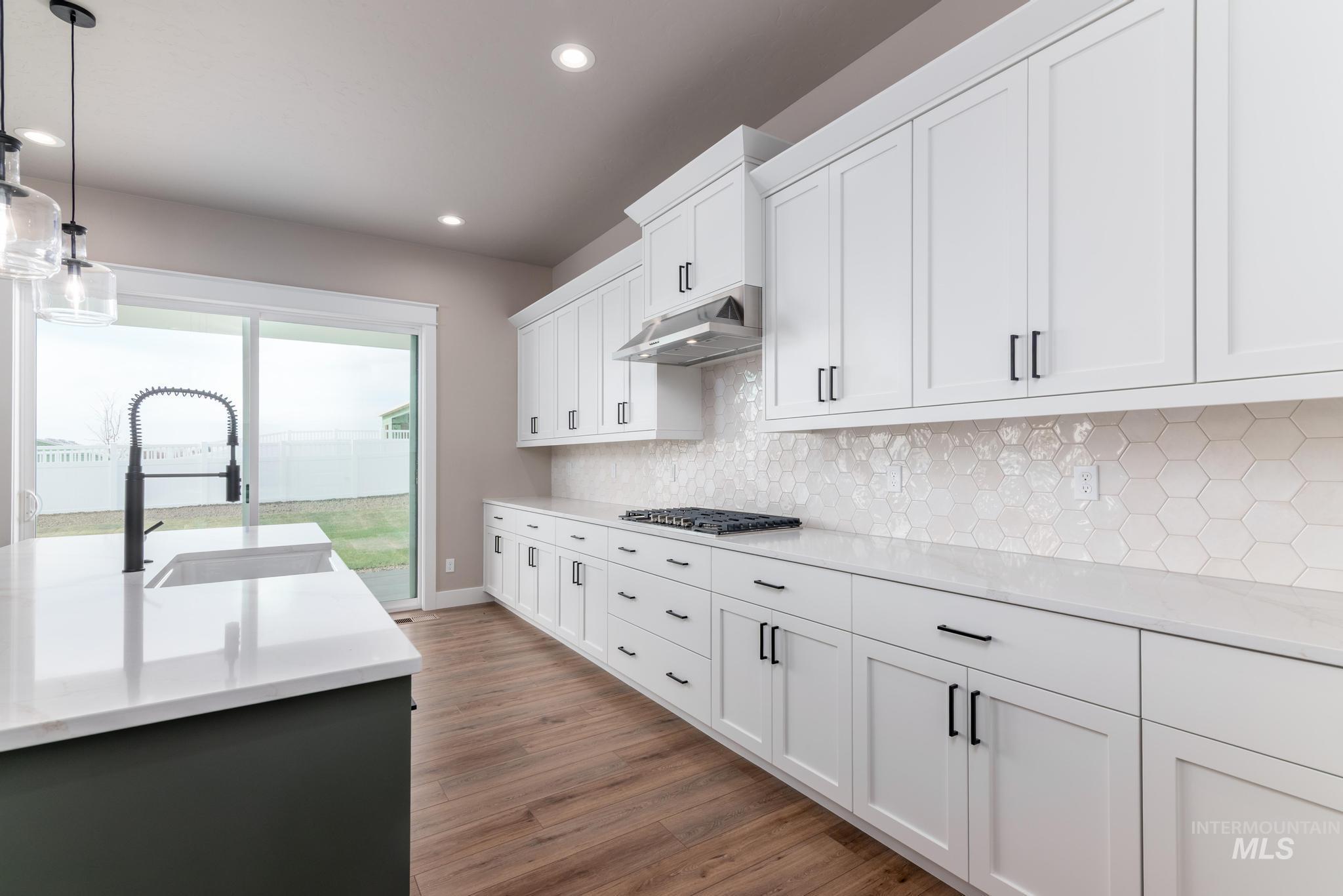 Kitchen featuring decorative light fixtures, light stone counters, white cabinetry, and recessed lighting