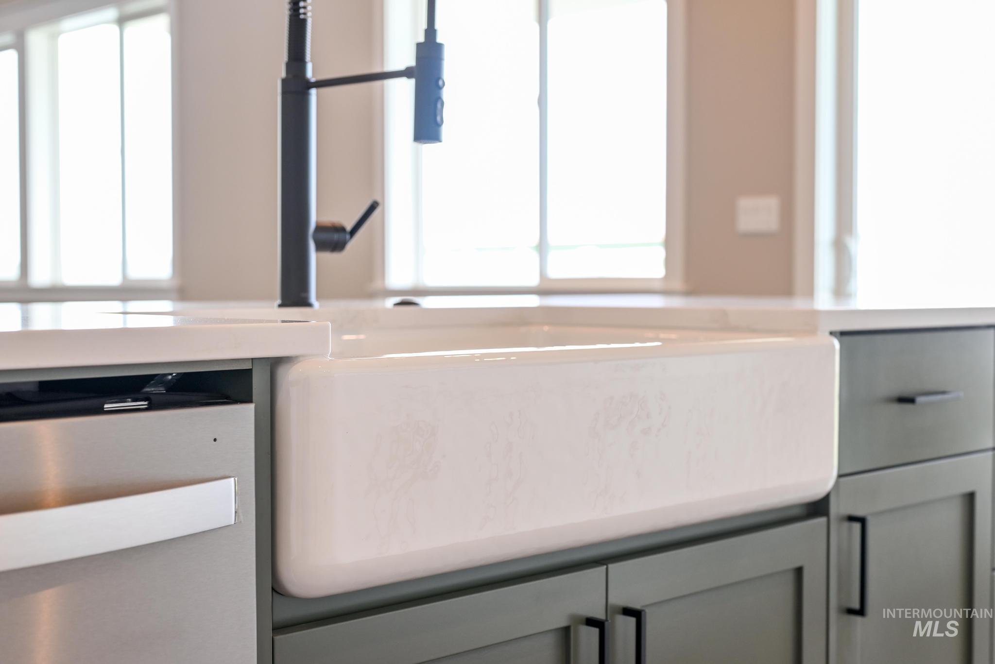 Kitchen view of gray cabinetry, stainless steel dishwasher, and hanging light fixtures