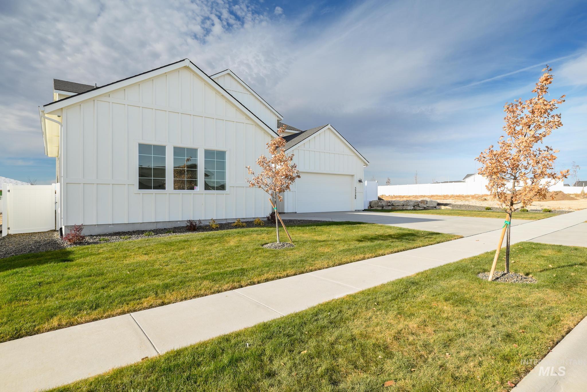 View of front of property with board and batten siding, driveway, and an attached garage