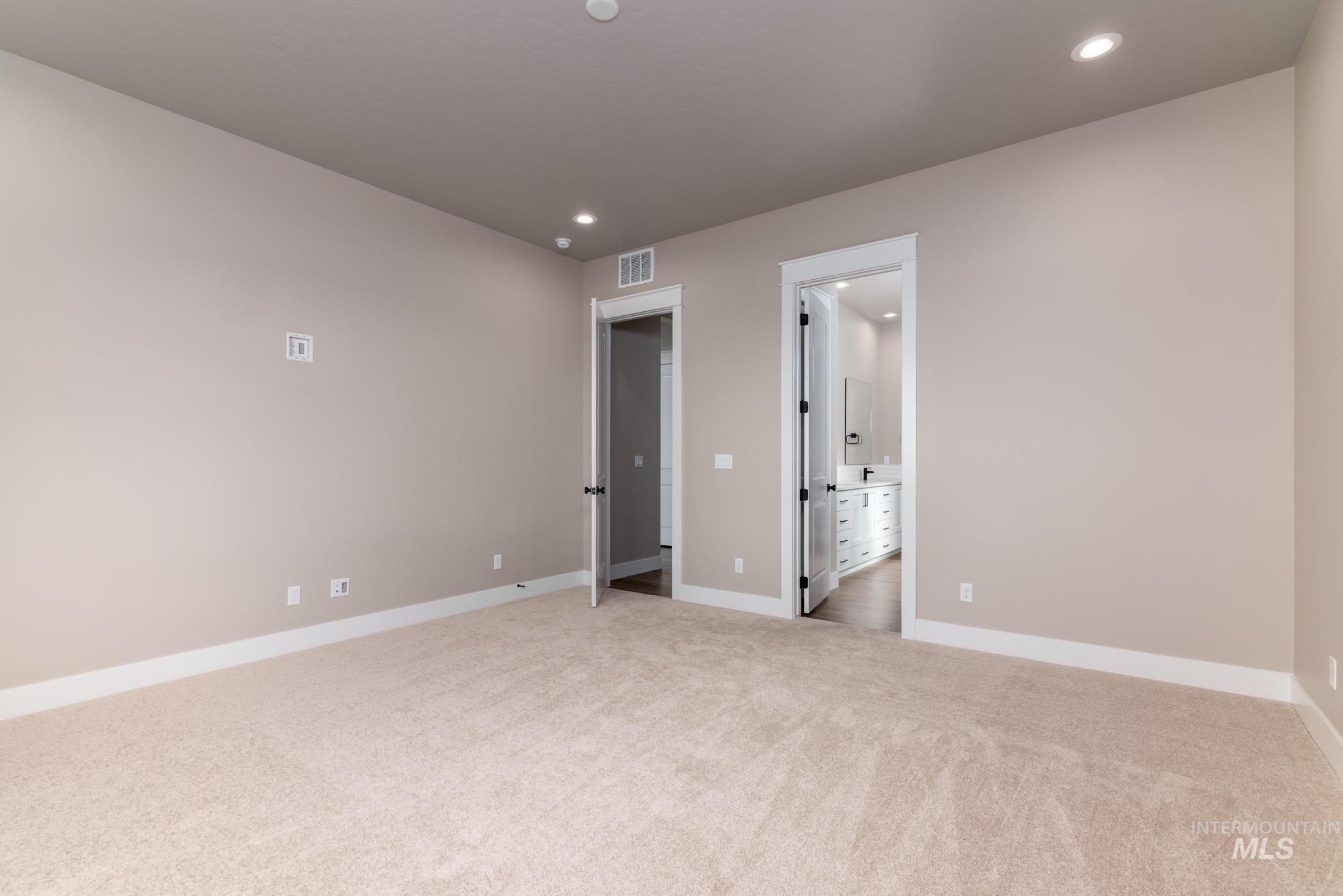 Unfurnished bedroom featuring recessed lighting, light carpet, and ensuite bath
