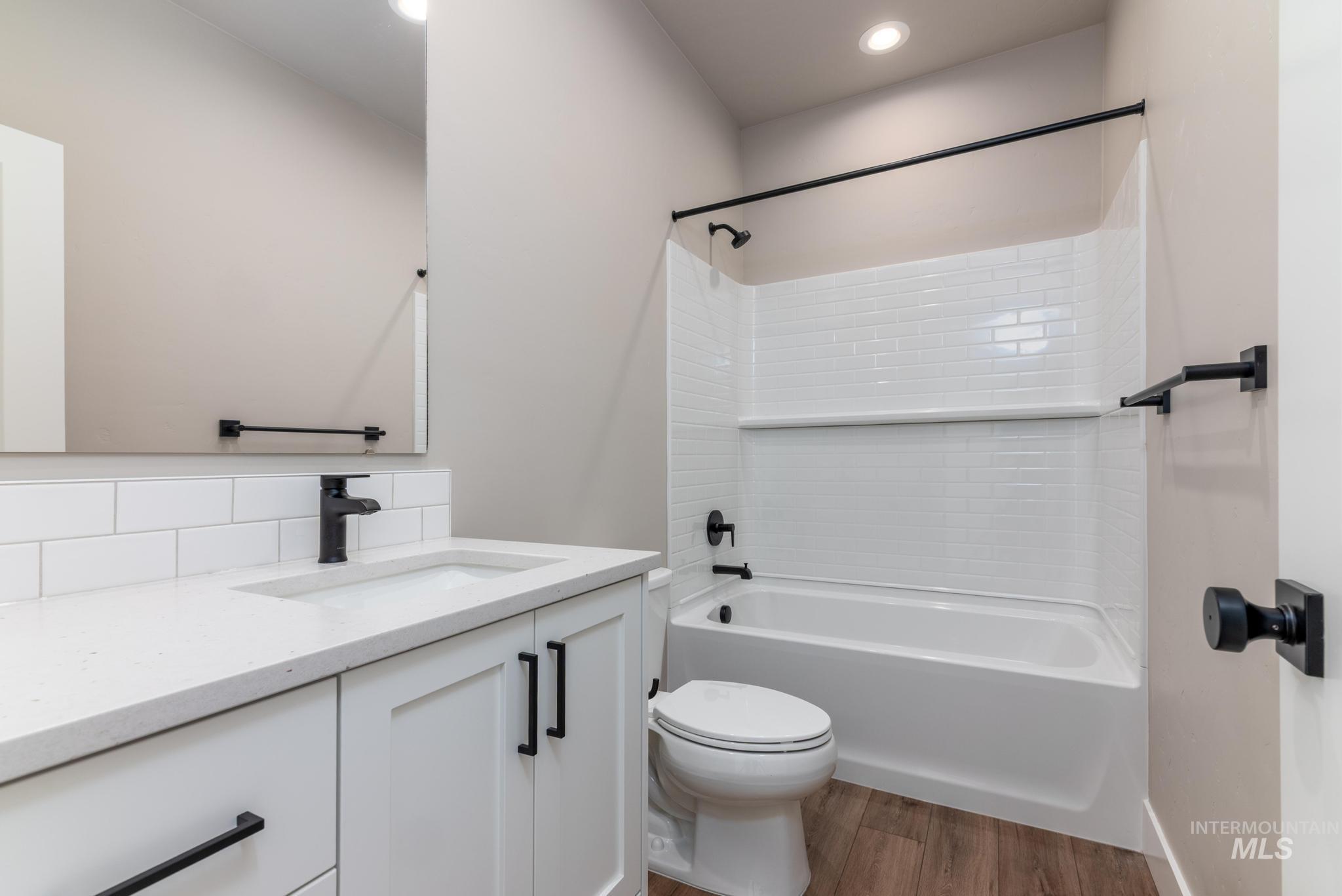 Bathroom featuring vanity, tub / shower combination, dark wood finished floors, and recessed lighting