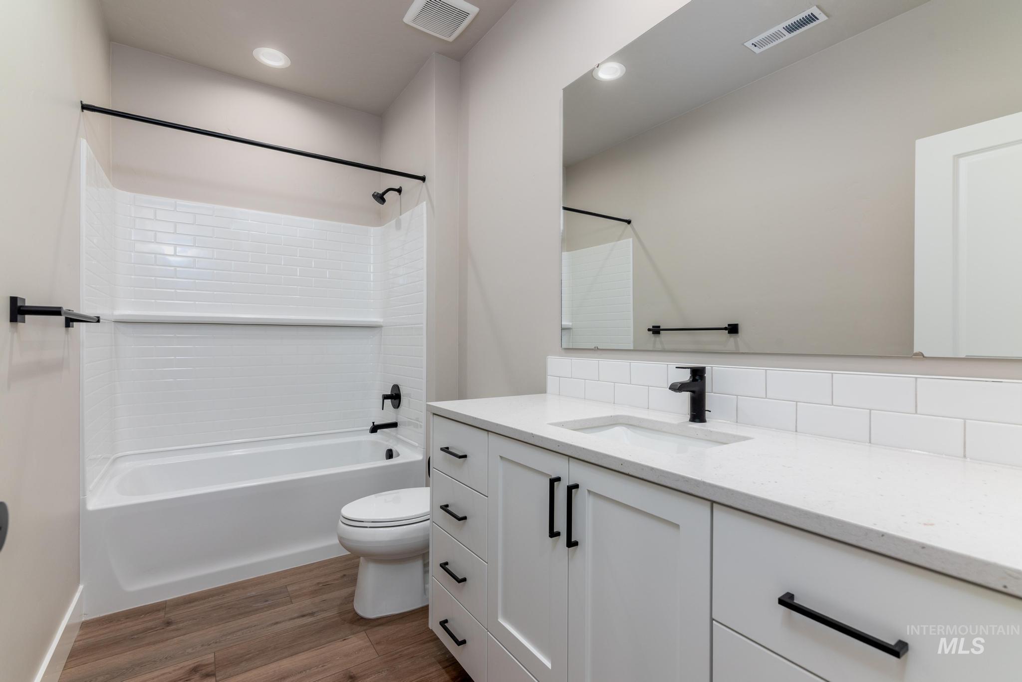 Bathroom featuring bathtub / shower combination, vanity, dark wood finished floors, recessed lighting, and backsplash