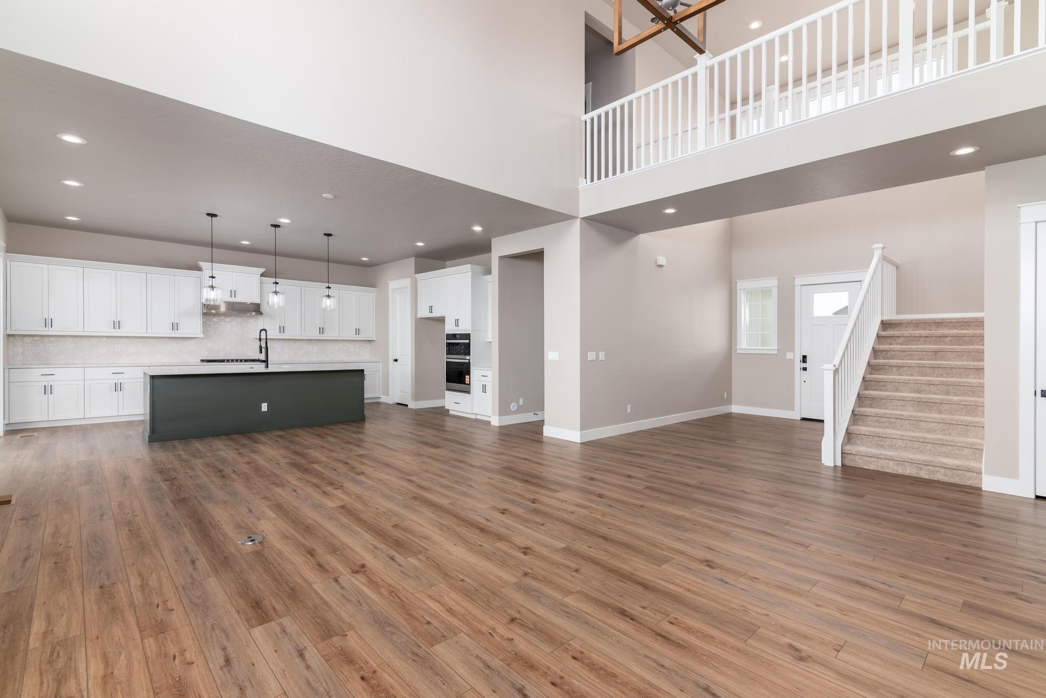 Unfurnished living room featuring stairs, dark wood-type flooring, recessed lighting, and a chandelier