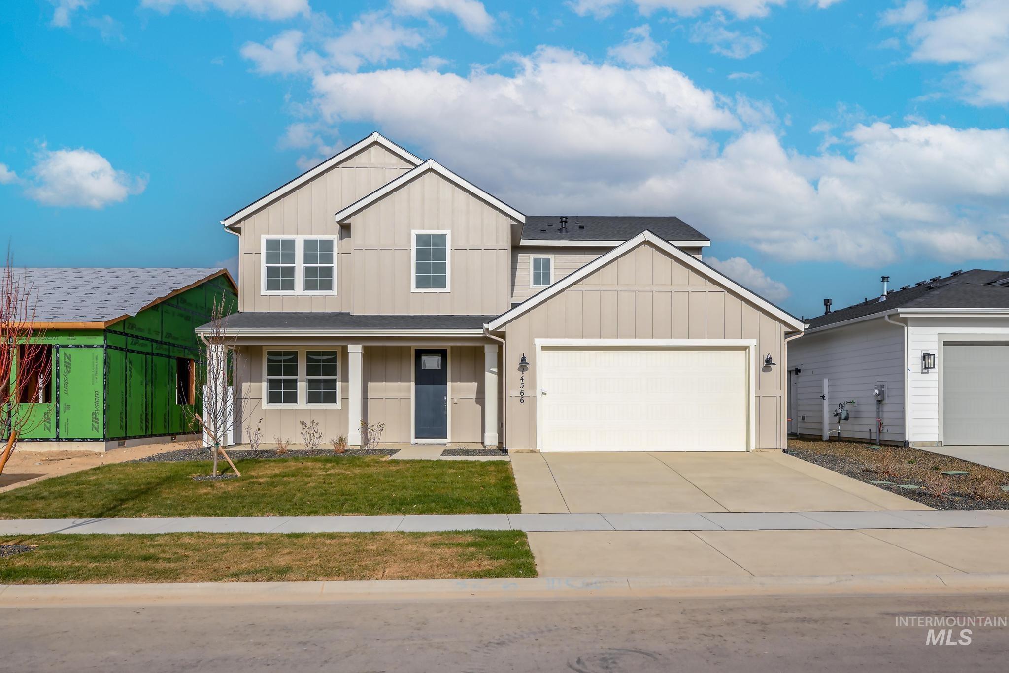 View of front of house with board and batten siding, a porch, driveway, and a front yard