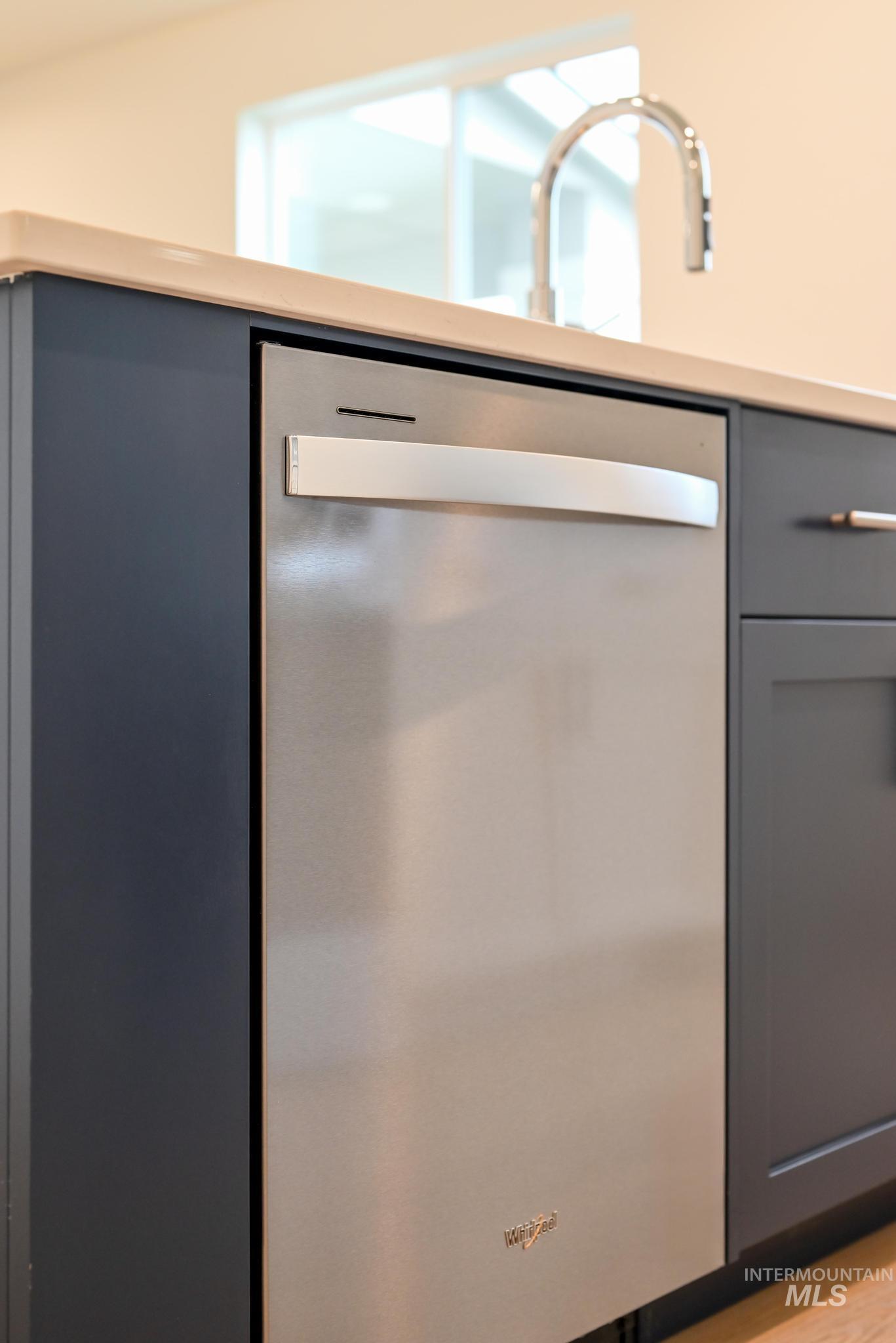 Kitchen view of gray cabinetry, stainless steel dishwasher, and light countertops