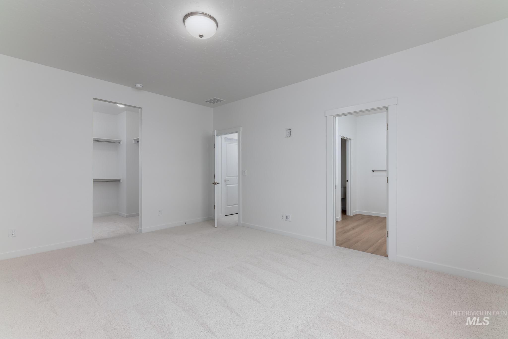 Unfurnished bedroom with a spacious closet and light colored carpet
