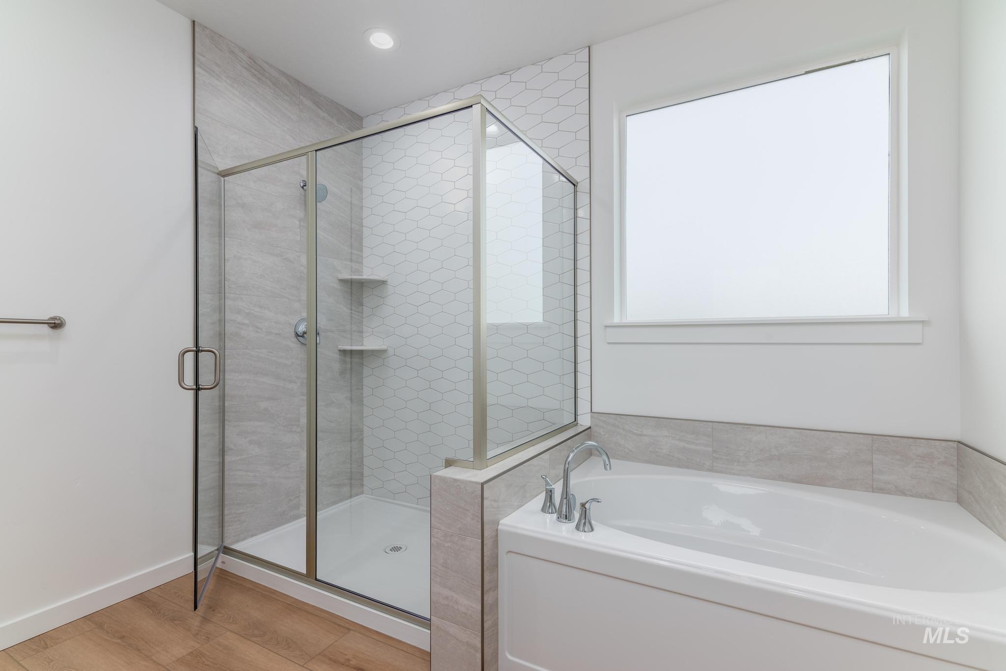 Full bathroom with a garden tub, a shower stall, and light wood-style floors