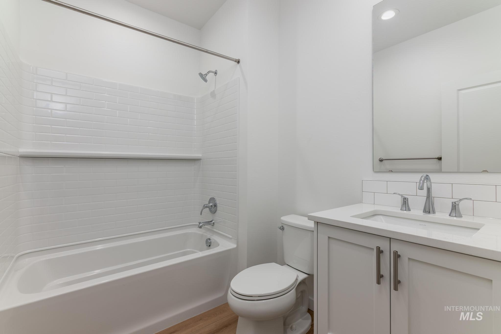Bathroom featuring bathing tub / shower combination, vanity, decorative backsplash, and light wood-style floors