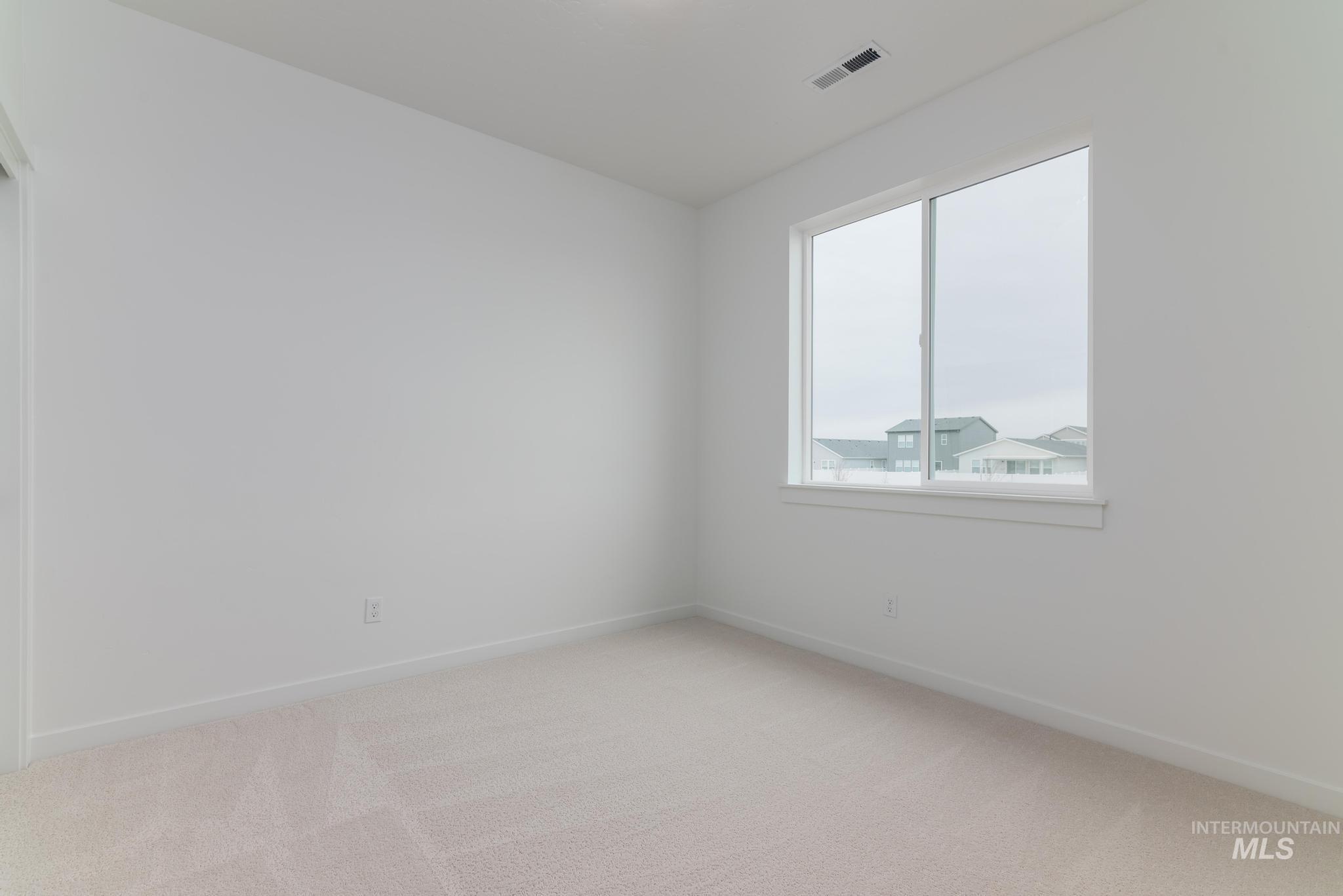 Empty room featuring light carpet and baseboards