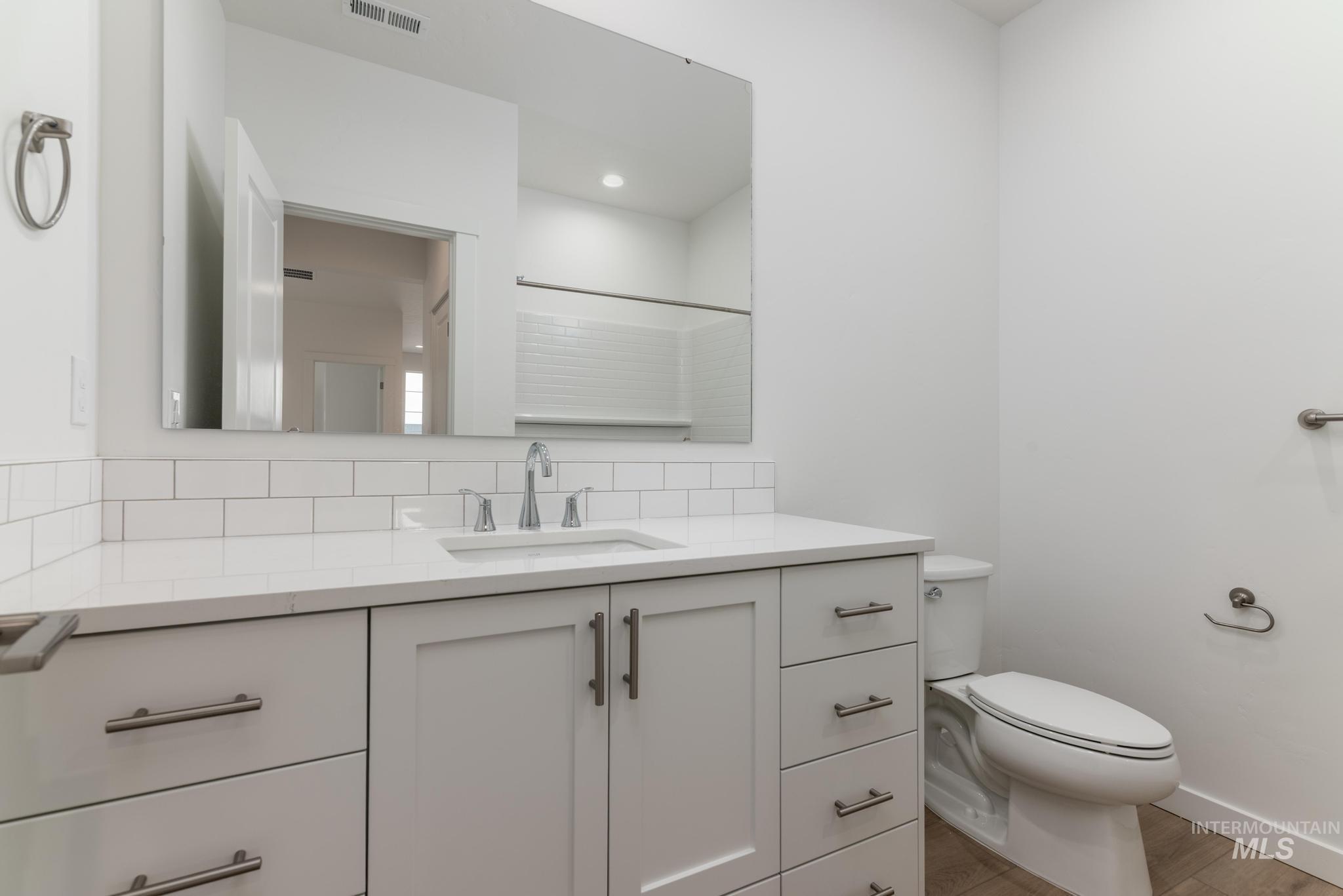 Bathroom featuring vanity, a shower, and tasteful backsplash