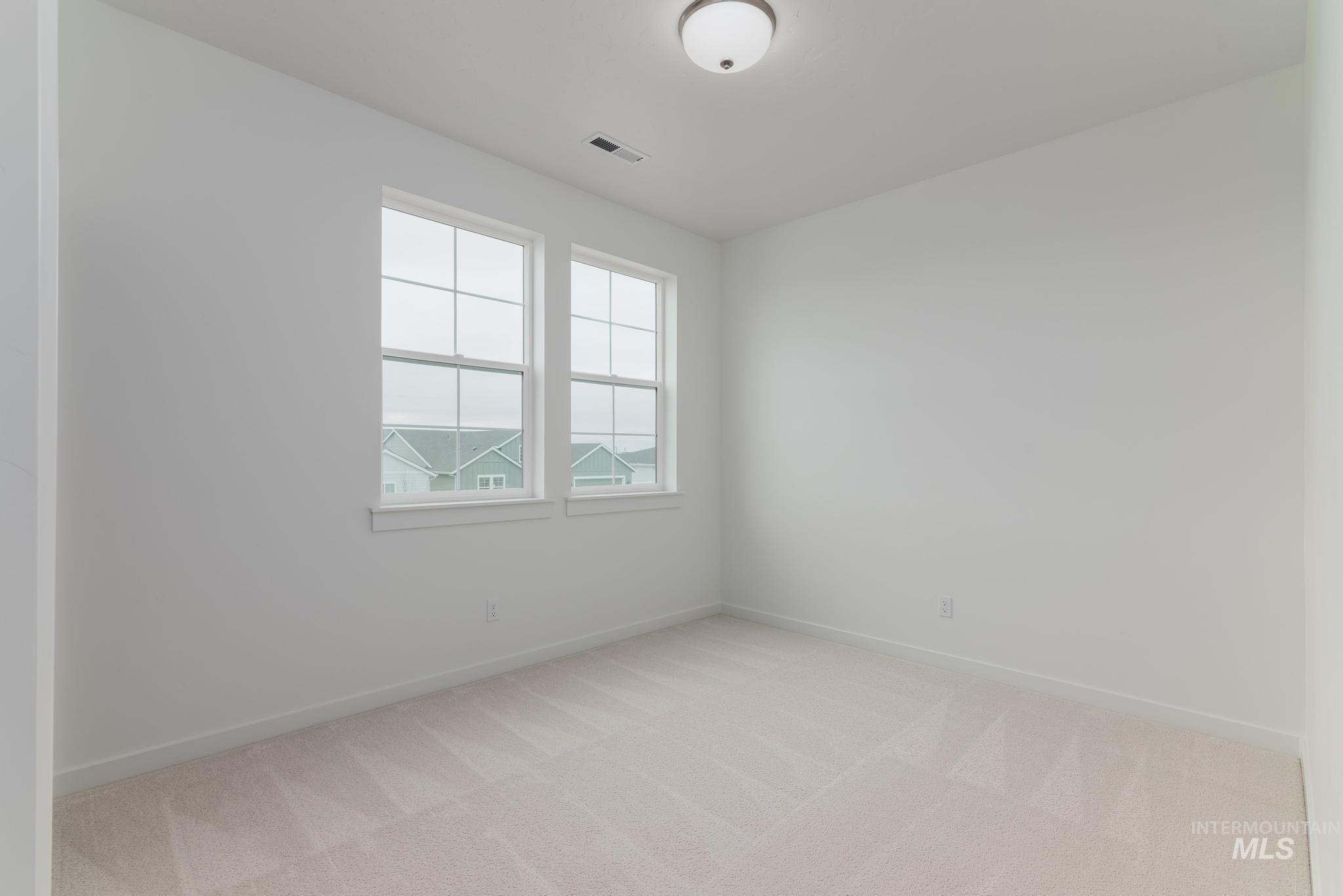 Spare room featuring light carpet and baseboards