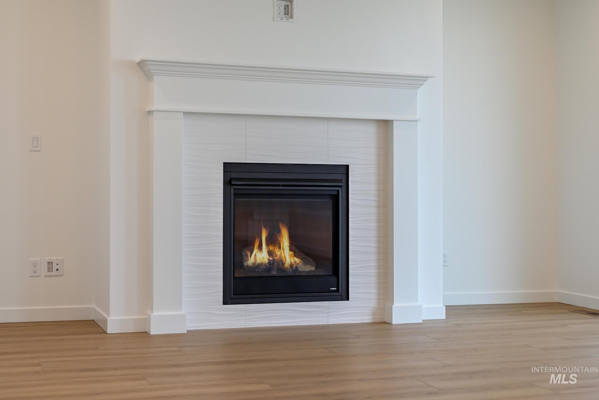 Detailed view of wood finished floors and a tiled fireplace