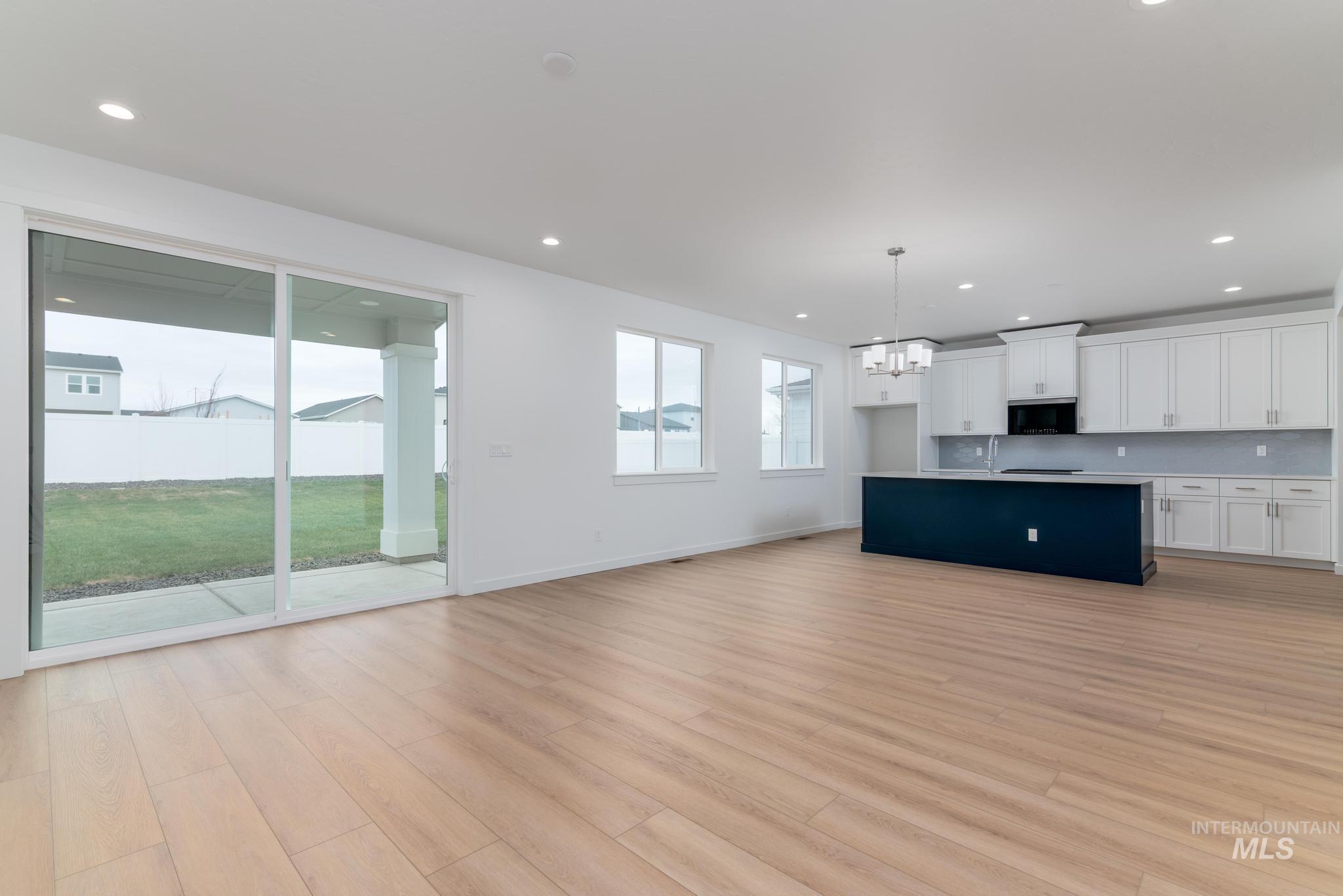 Kitchen with white cabinets, open floor plan, an island with sink, hanging light fixtures, and a chandelier