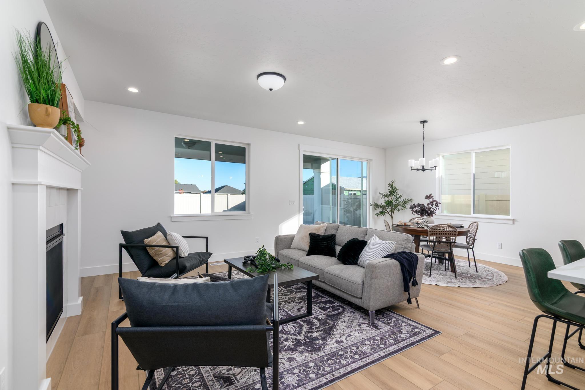 Living room featuring recessed lighting, a fireplace, light wood finished floors, and a chandelier