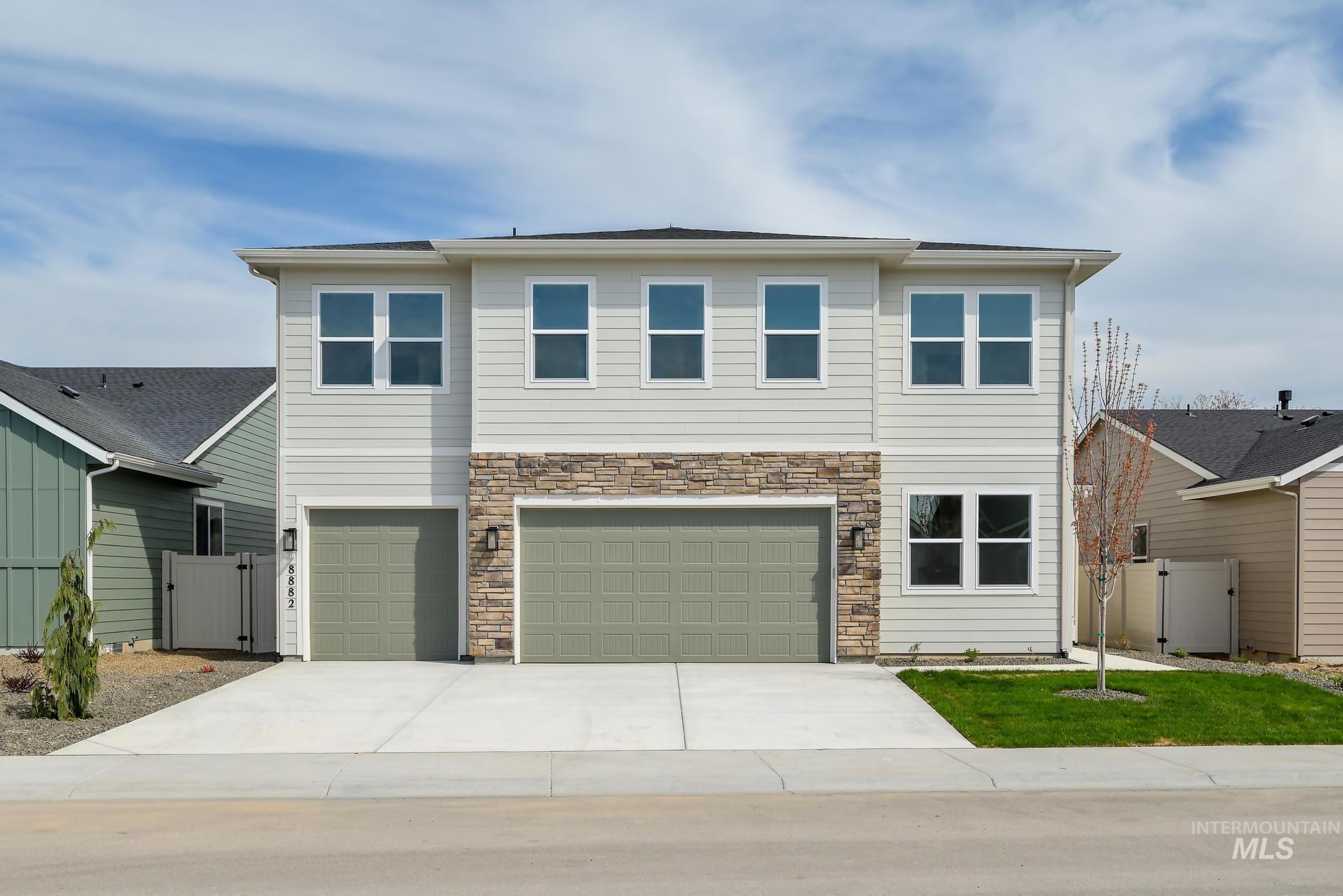 View of front of house featuring concrete driveway, a garage, stone siding, and a gate