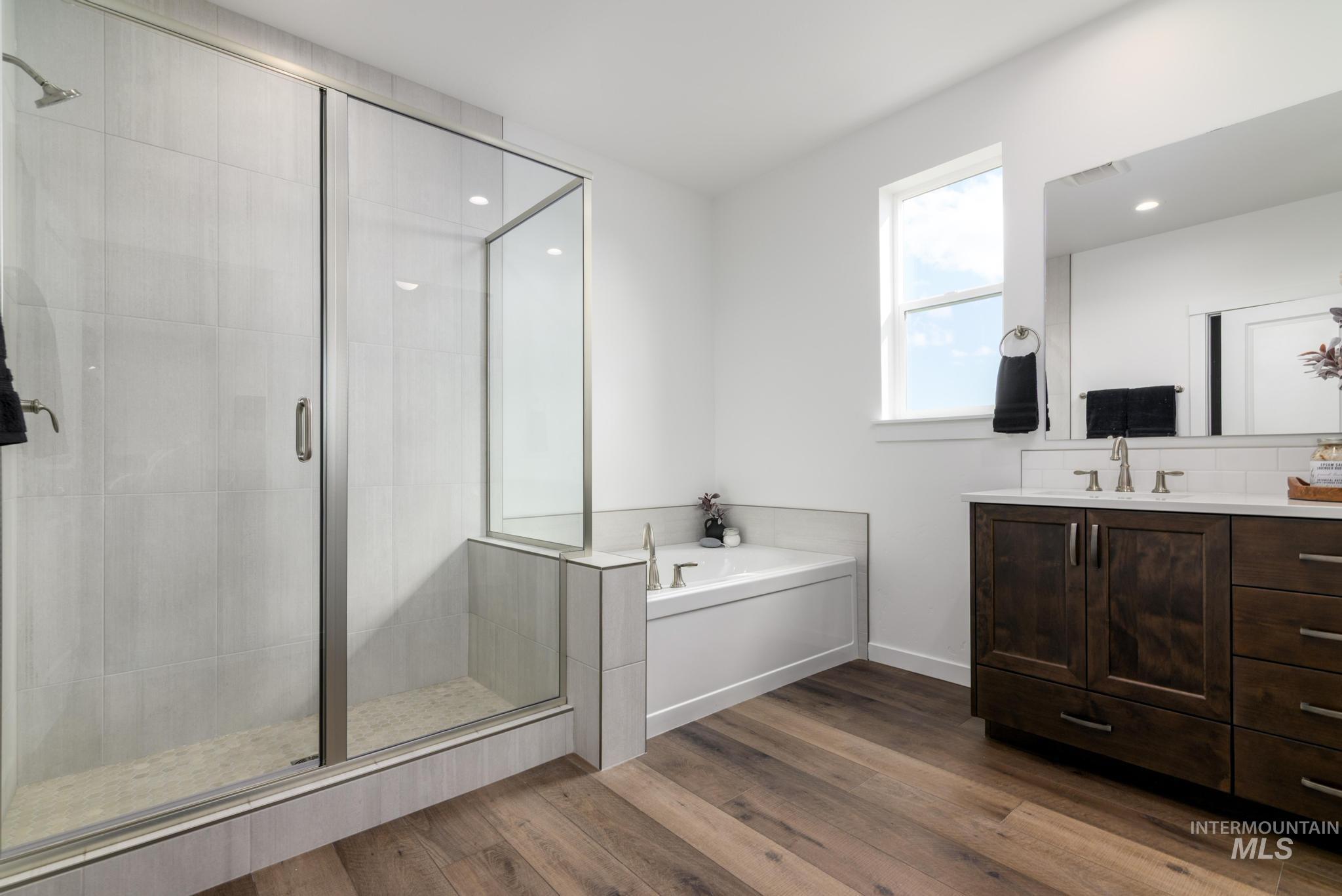 Full bath with vanity, a garden tub, a shower stall, and dark wood-type flooring
