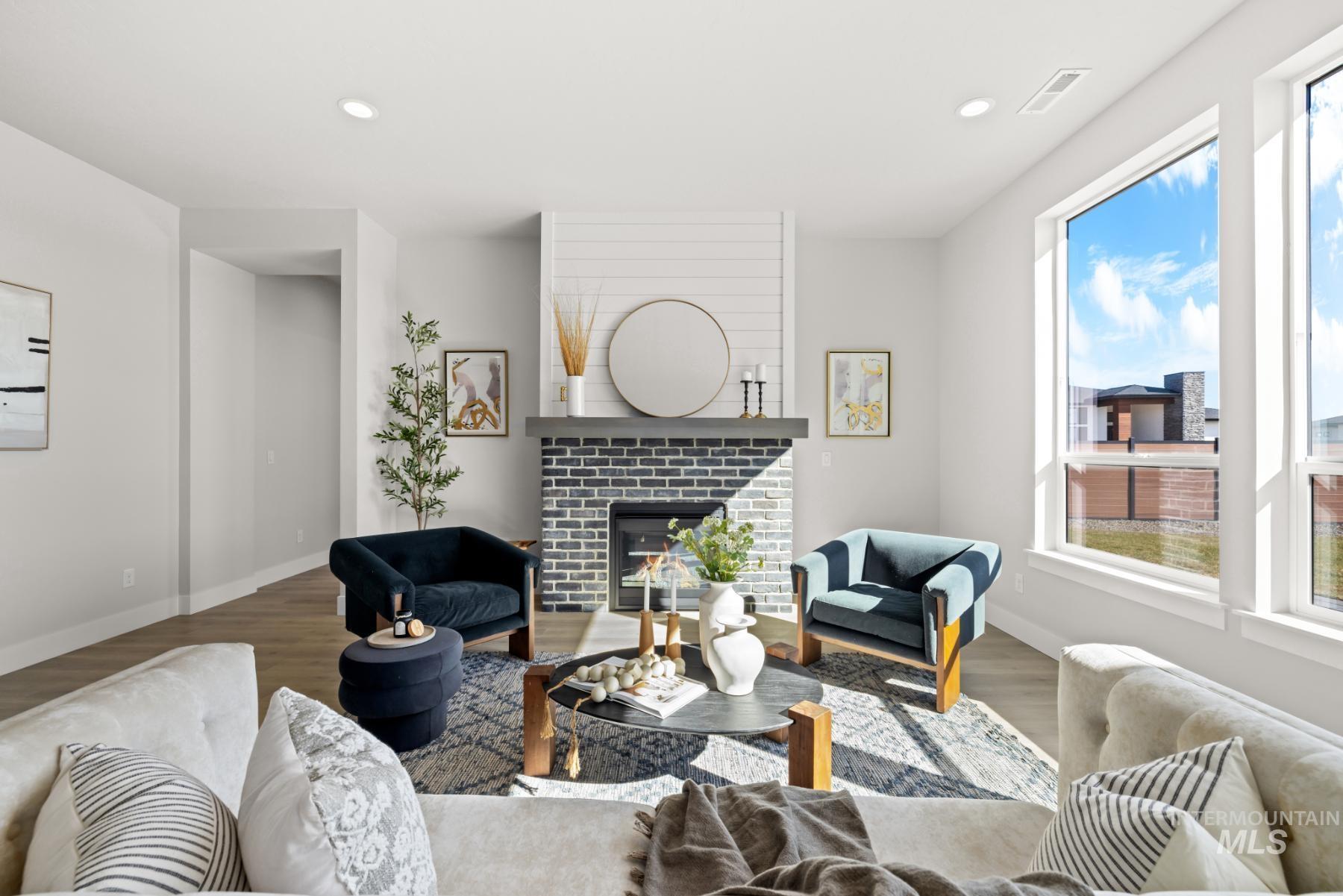 Living room with a brick fireplace, wood finished floors, and recessed lighting