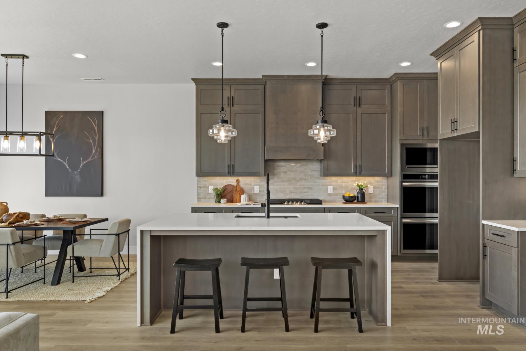 Kitchen featuring a center island with sink, recessed lighting, light stone countertops, decorative backsplash, and a breakfast bar area