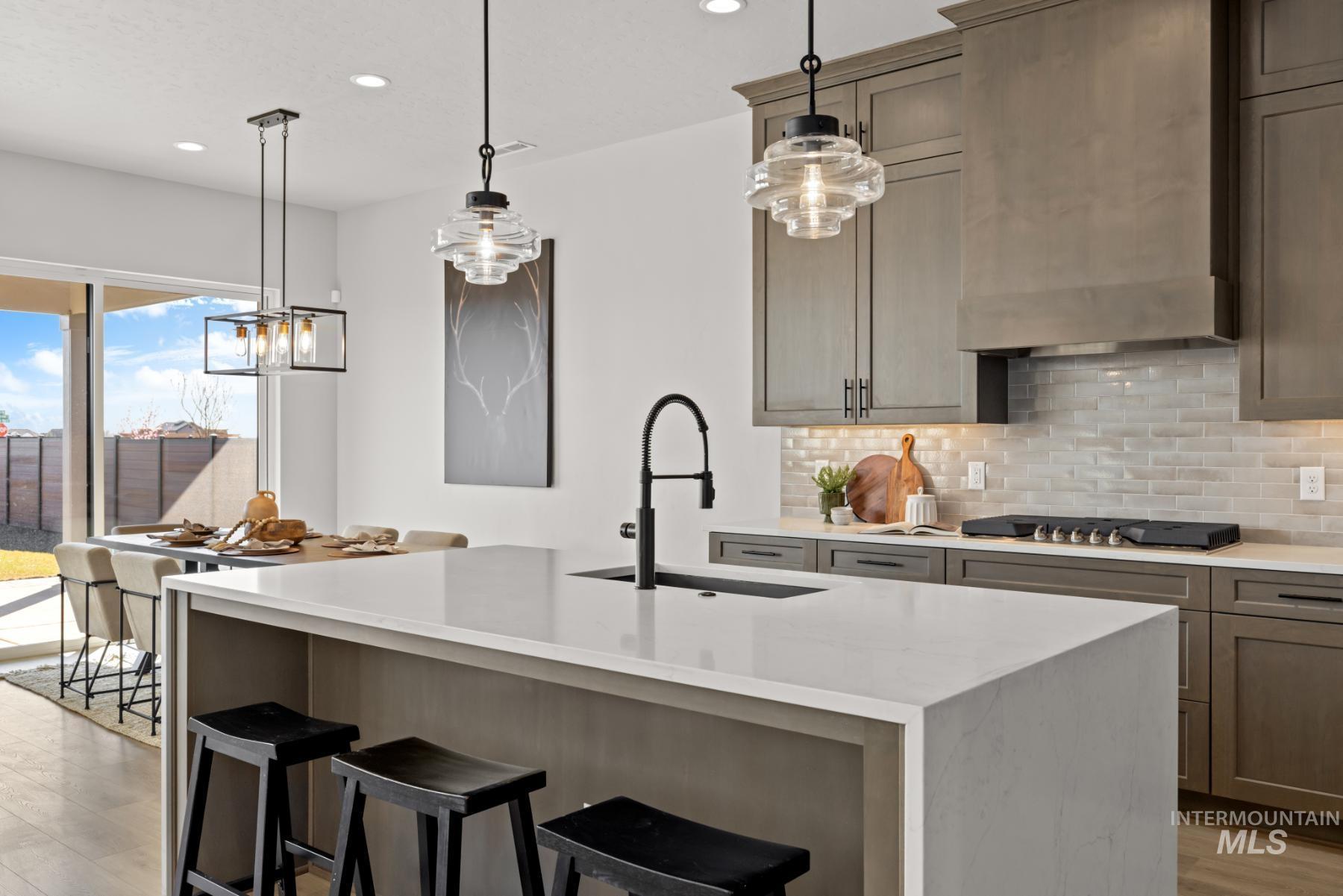 Kitchen featuring decorative backsplash, a kitchen bar, decorative light fixtures, light stone countertops, and recessed lighting