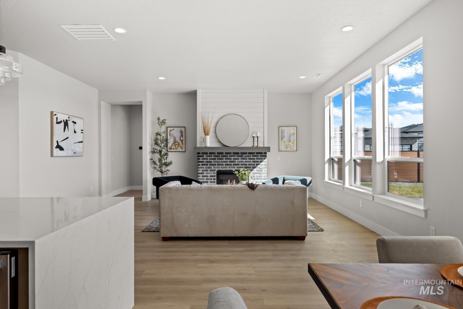 Living room with light wood finished floors, a lit fireplace, and recessed lighting