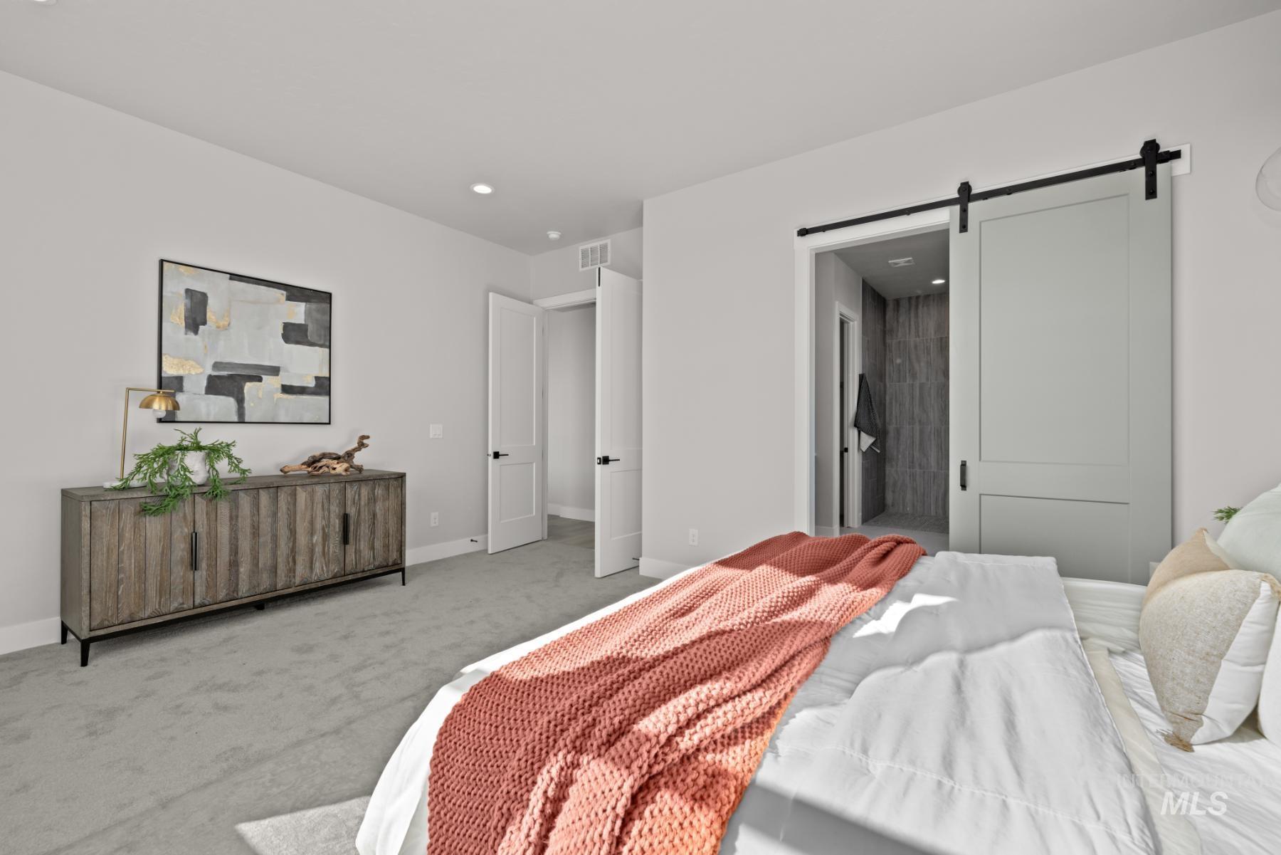 Carpeted bedroom with a barn door, connected bathroom, and recessed lighting